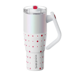 White travel mug with pink polka dots, clear lid, and a white ergonomic handle on the right side.