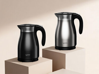 two cordless electric kettles, black and stainless steel, displayed on beige blocks in a studio setting.