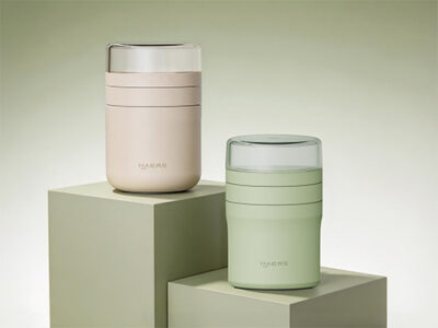 two pastel haers insulated cups, one pink-beige and one sage green, displayed on pale green blocks.