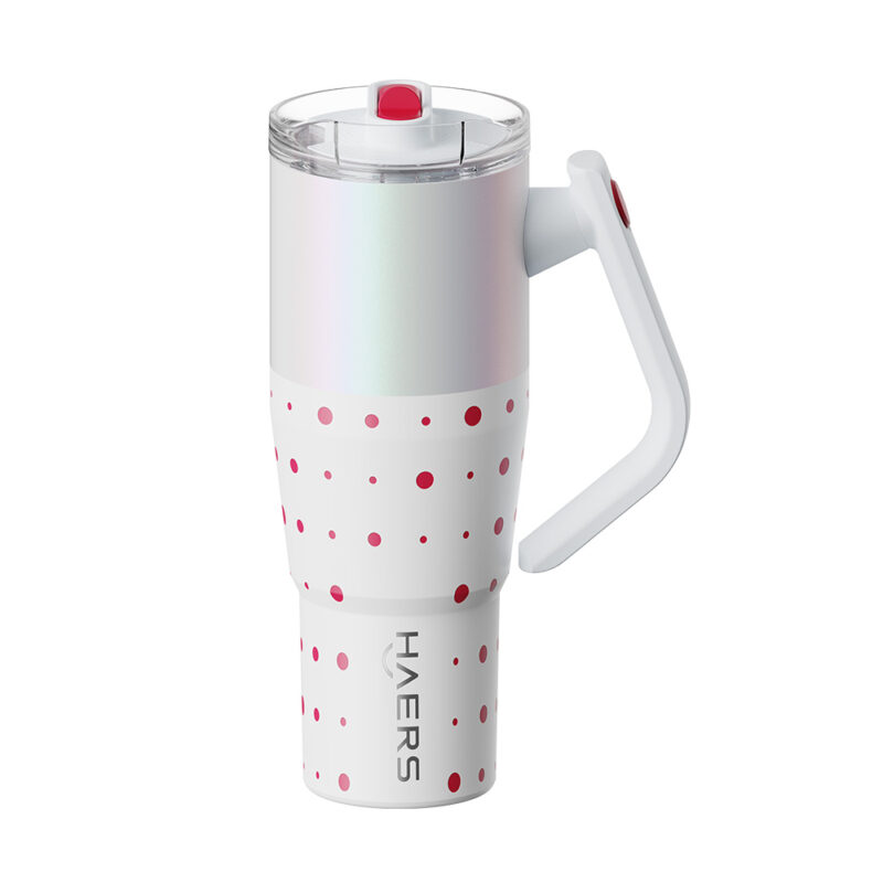 white insulated travel mug with pink polka dots, clear lid, and integrated handle.