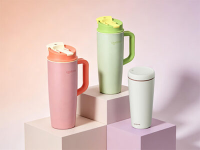 three pastel travel mugs on stepped, pastel blocks with a soft gradient background in pinks and purples.`note: ensure no stray punctuation that could disrupt screen readers`